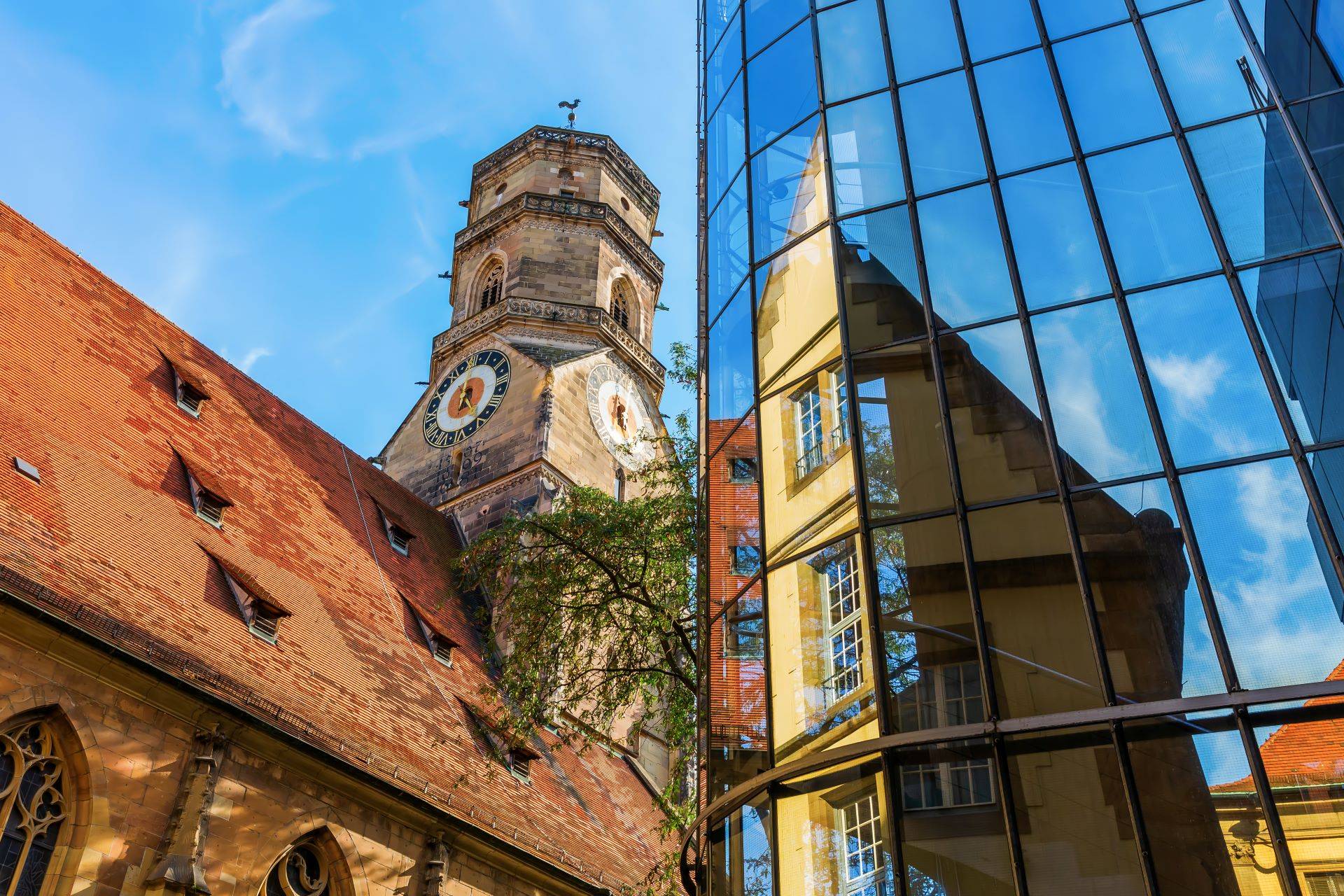 Turm mit Uhr und Glasfassade in Stuttgart, Verbindung von Tradition und Moderne.