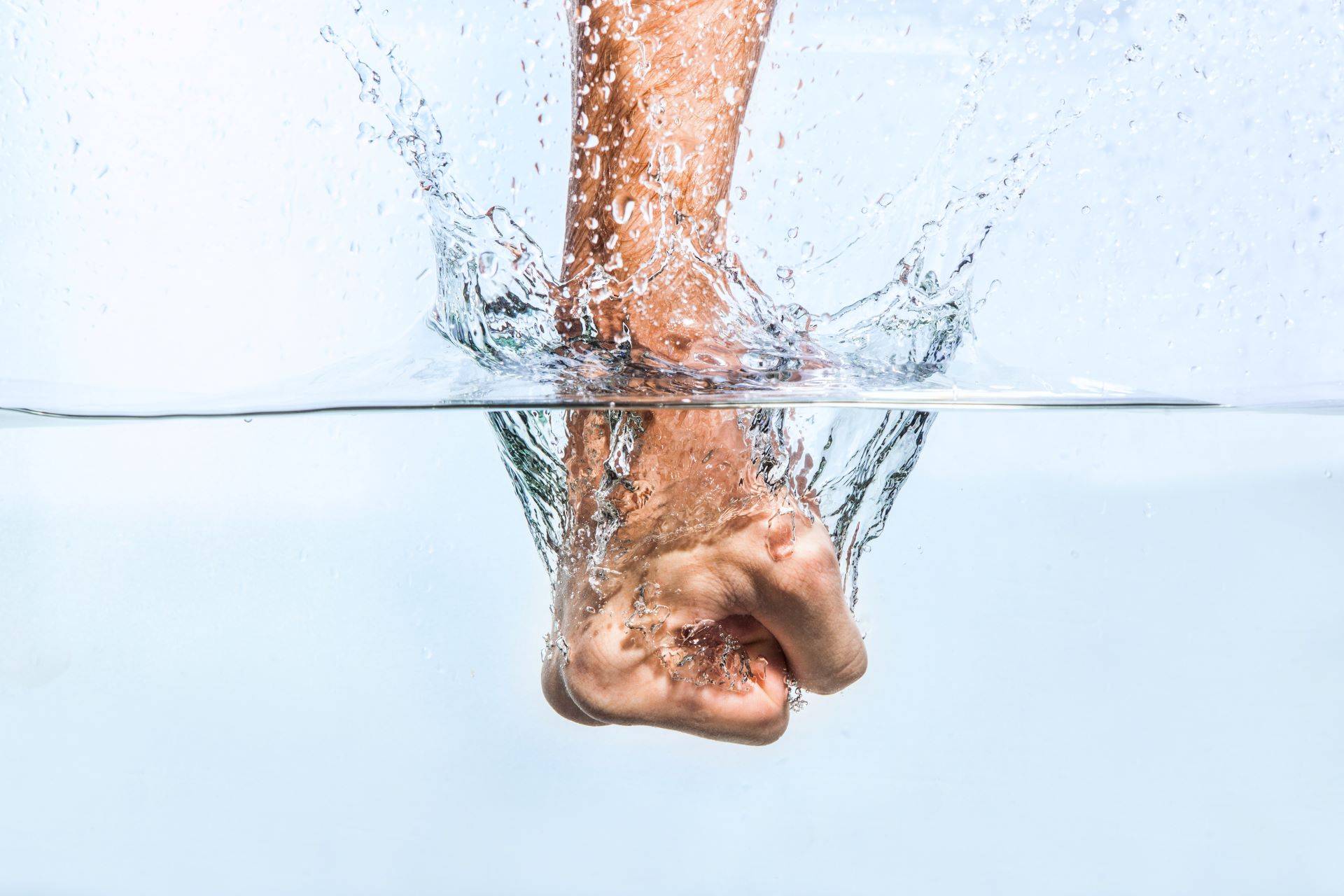 Faust durchbricht Wasseroberfläche mit Spritzern